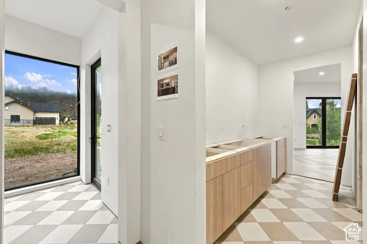 Interior space featuring light wood-finish cabinetry, checkered pattern tile flooring, recessed lighting, and large windows with black frames