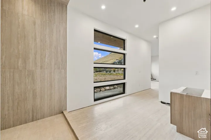 Stacked horizontal windows, large-format neutral wall https://assets.utahrealestate.com/photos/280x210/2180751_9e4c6187f683311e15e63405935fac7c_6ad15896a852a.jpgtile, recessed ceiling lighting, wood-finish cabinetry, and wide-plank tile flooring