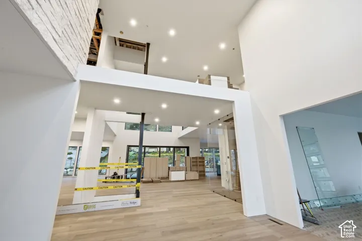 Two-story interior with recessed lighting, light wood-finish flooring, and a glass-paneled barrier