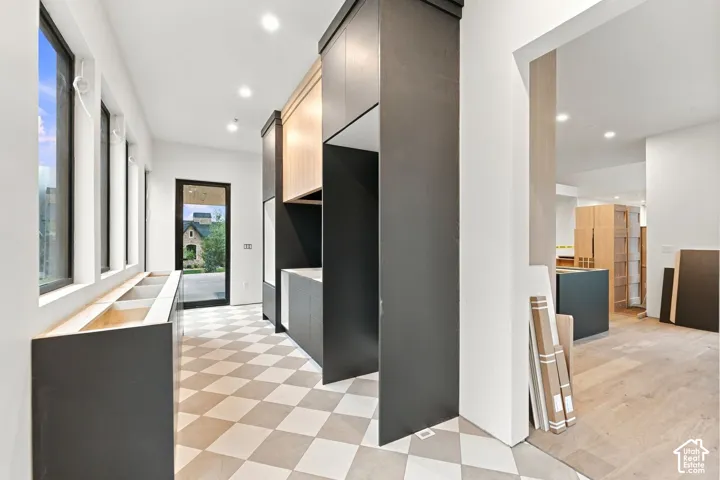 Custom cabinetry featuring dual-tone matte black and light wood finishes, geometric checkered tile flooring, recessed lighting, and expansive windows
