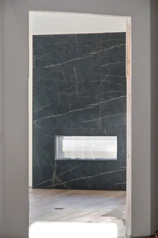 Black marble-look tile accent wall with gold veining, featuring a rectangular built-in electric fireplace