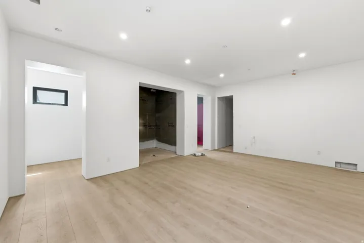 Recessed lighting, wood-finish flooring, white walls, multiple doorways, and a rectangular window