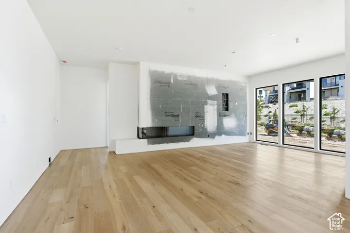 Interior featuring wood-finish flooring, recessed lighting, expansive windows with black frames, and a built-in linear fireplace
