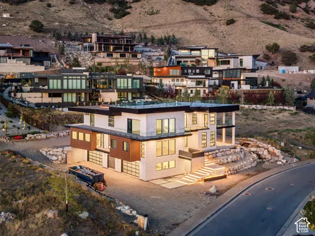 Modern architectural design featuring multi-level construction, extensive window placements, multiple garage doors, and illuminated exterior steps