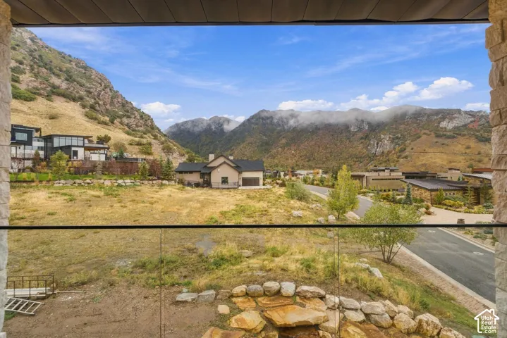 Covered deck with a glass balustrade featuring stone-clad columns and expansive mountain scenery