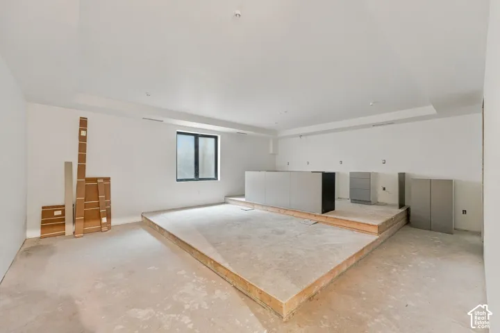 Multi-level room featuring a raised platform, recessed ceiling detail, and built-in cabinetry base