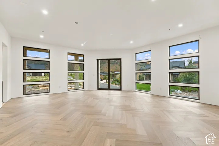 Herringbone wood-finish flooring, recessed lighting, and multiple horizontal windows with dark frames