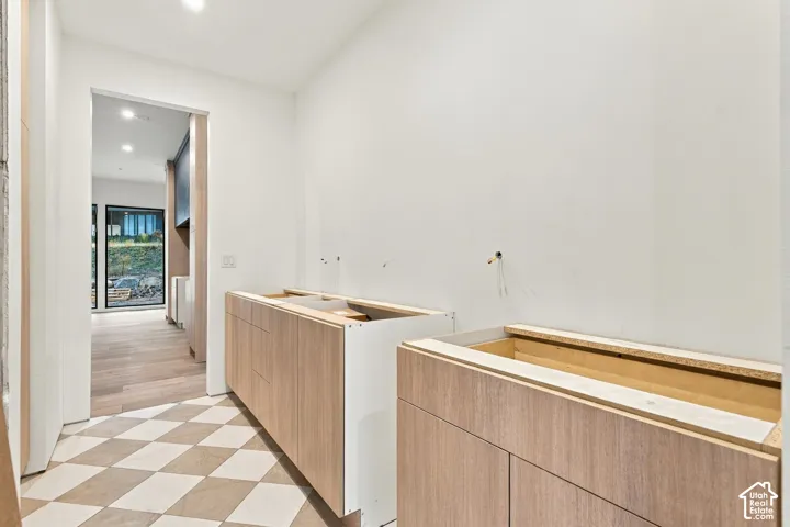 Light wood-finish cabinetry, geometric tile flooring, and recessed ceiling lighting