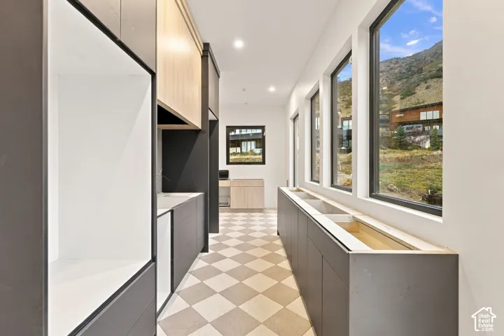 Custom cabinetry featuring dual-tone wood and matte finishes, expansive windows, recessed lighting, and a geometric-patterned tile floor