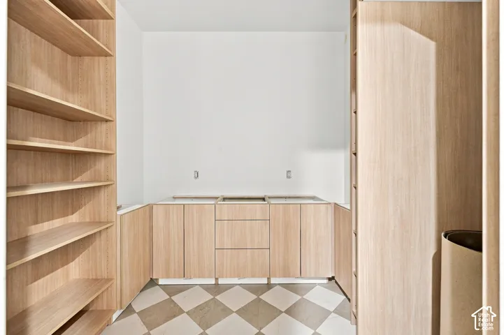 Built-in cabinetry featuring wood-finish cabinetry, integrated open shelving, flat-panel doors, drawers, and checkered tile flooring