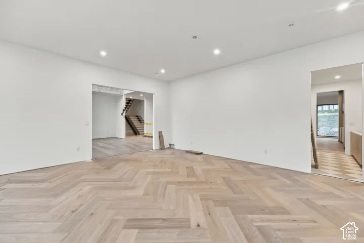 Herringbone wood-finish flooring, recessed lighting, and neutral wall finishes
