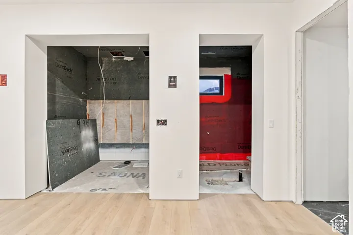 Structural framing for a dedicated sauna and cold plunge area featuring unfinished interior wall substrates and wood-finish flooring