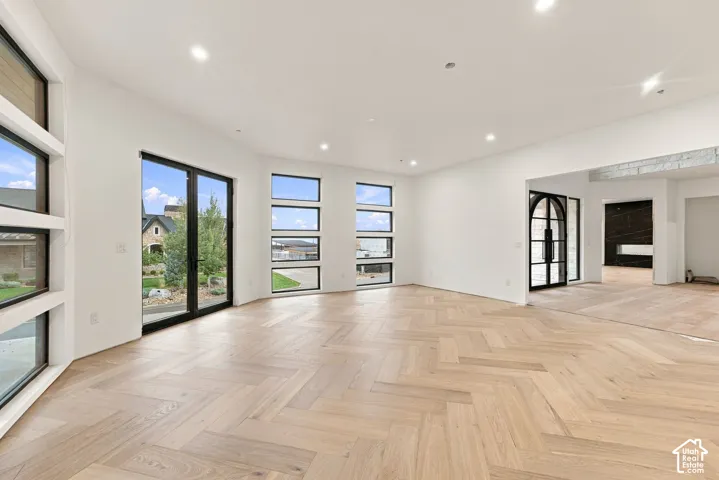 Herringbone wood-finish flooring, multi-pane window configurations, double-door exterior entry, recessed ceiling lighting, and smooth white wall finishes