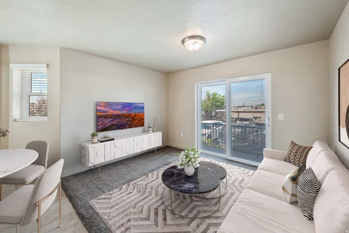 Neutral tone wall color, recessed ceiling lighting, sliding glass door with balcony, window with blinds, and durable flooring. *Virtually staged photo.