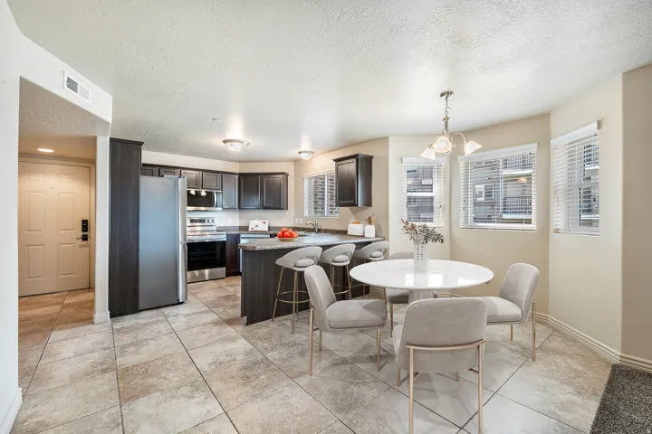Modern kitchen featuring dark wood-finish cabinetry, stainless steel appliances, and a granite-style countertop with a breakfast bar. *Virtually staged photo.