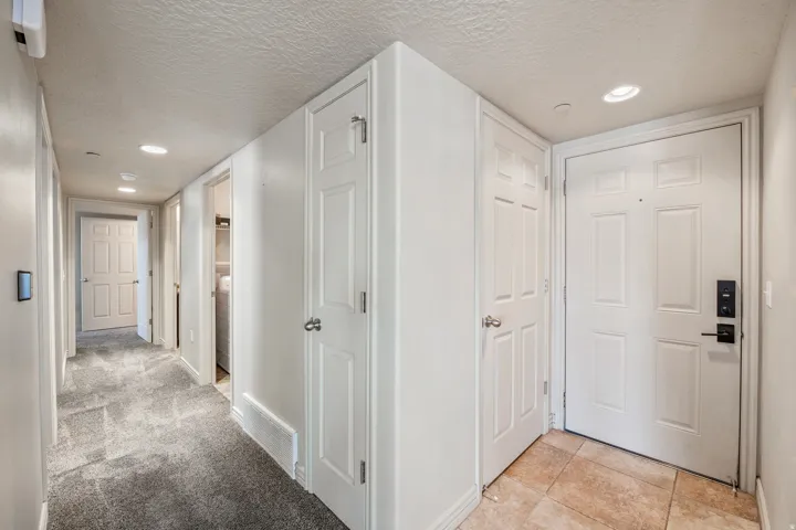 Entryway with neutral tile flooring, recessed lighting, and a paneled entry door with a digital lock
