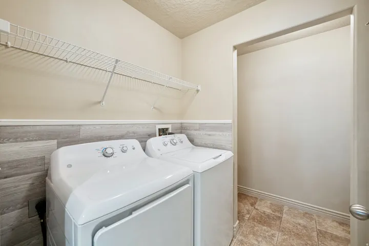 Laundry area featuring wire shelving, wood-finish wall paneling, and patterned floor tile