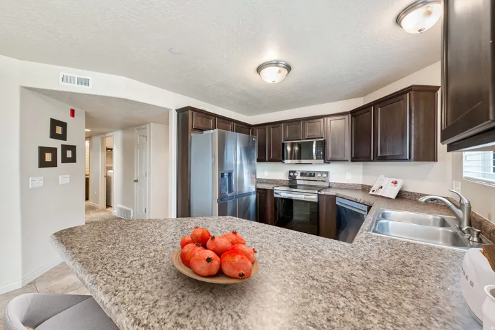 Contemporary kitchen featuring espresso-finish cabinetry with stainless steel appliances, including a gas range and refrigerator. *Virtually staged photo.