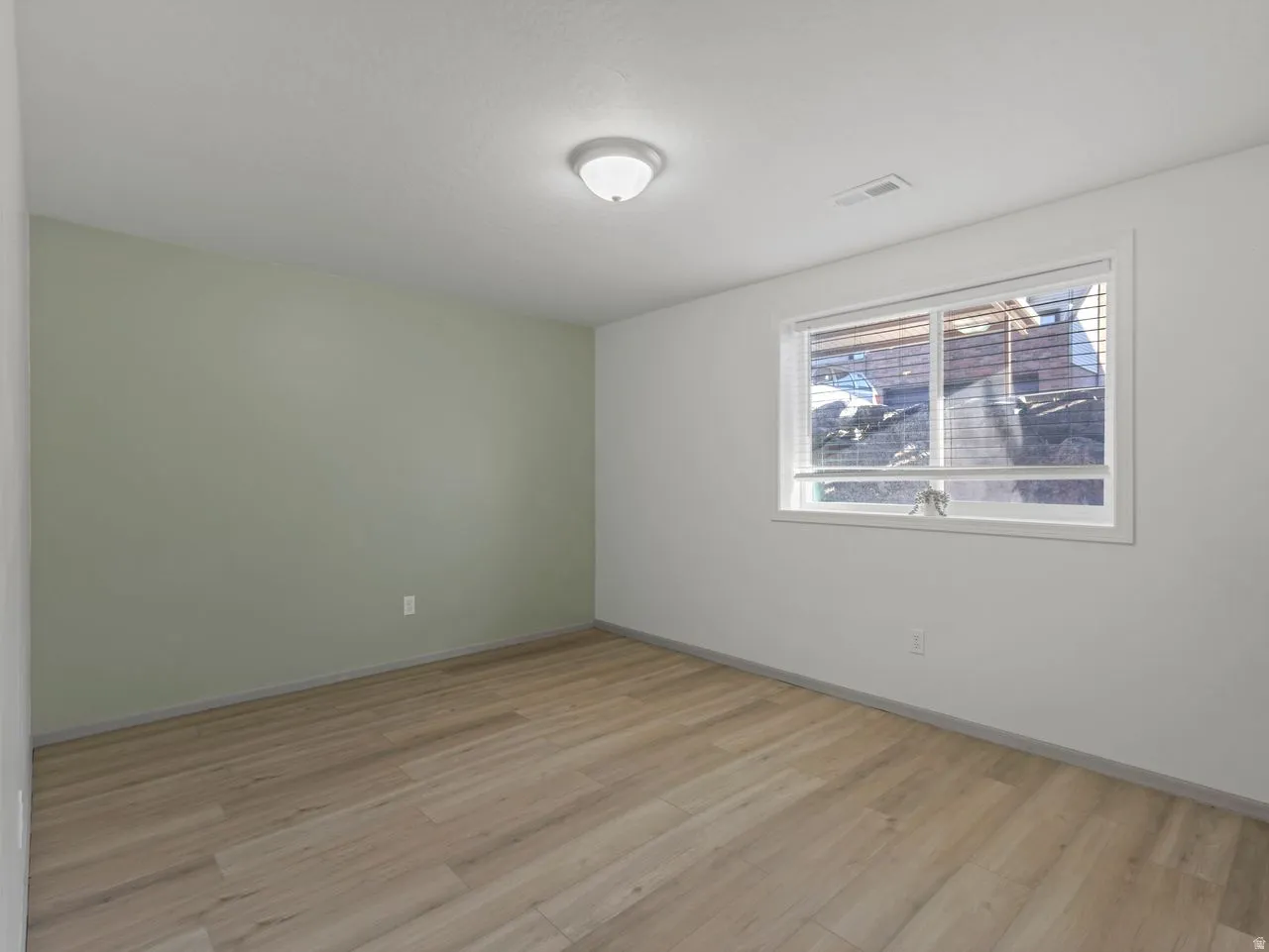 Recessed window with horizontal blinds, wood-finish flooring, overhead flush-mount lighting, and light-toned painted walls