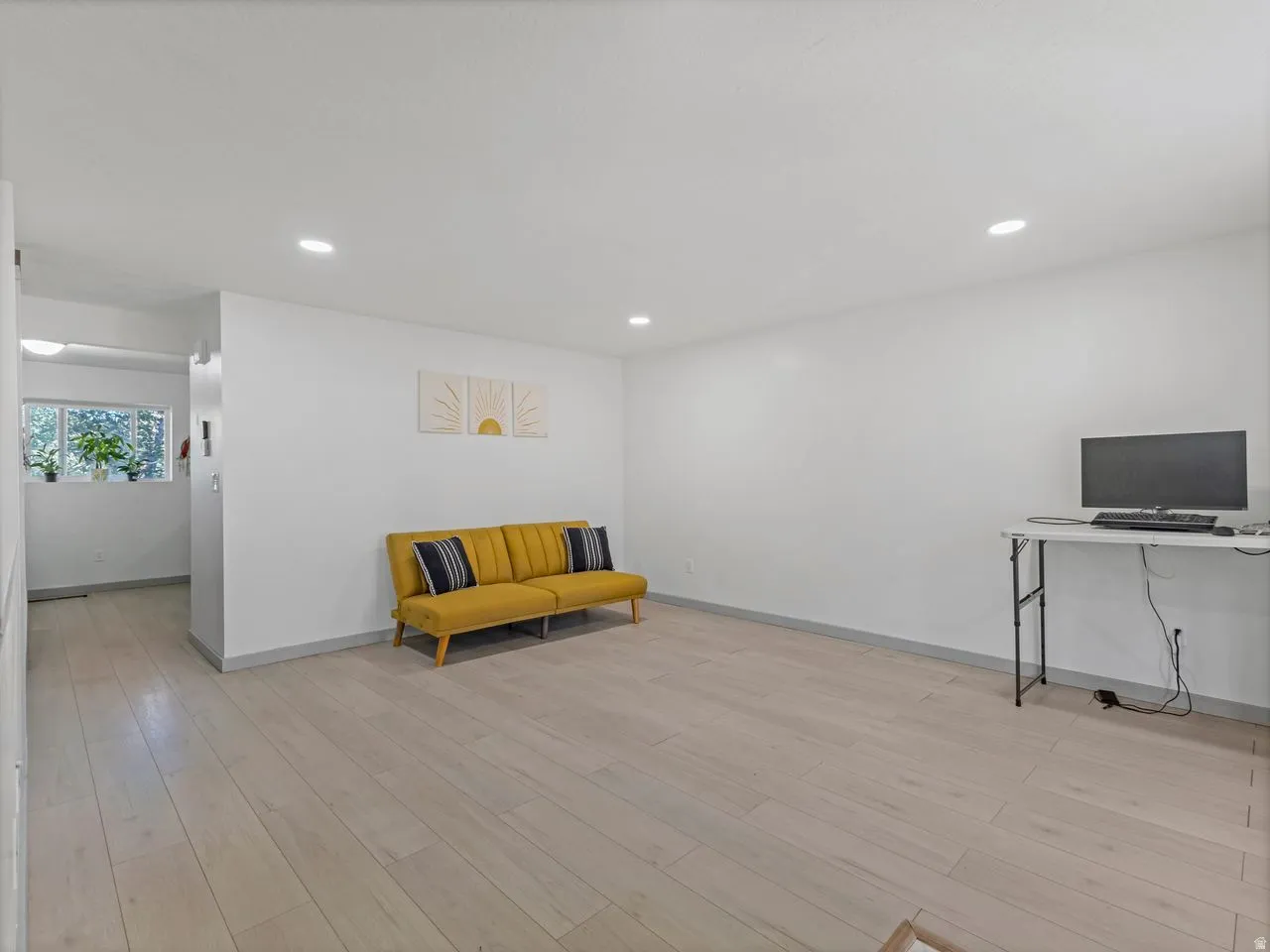 Recessed lighting, light wood-finish flooring, white wall finishes, and a window with natural light