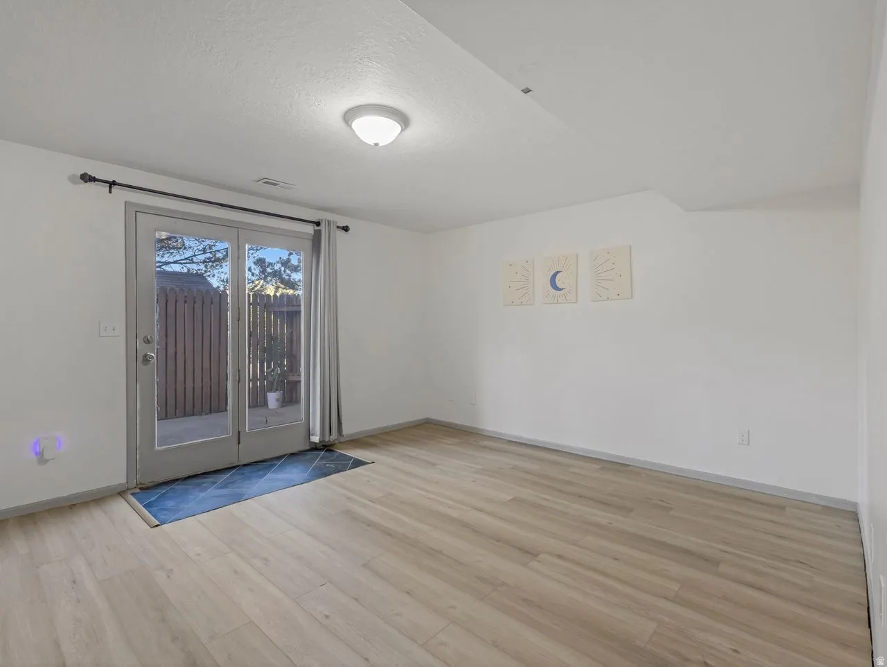 Bright, open living space with wood-finish flooring, glass sliding doors with natural light, and neutral wall finishes
