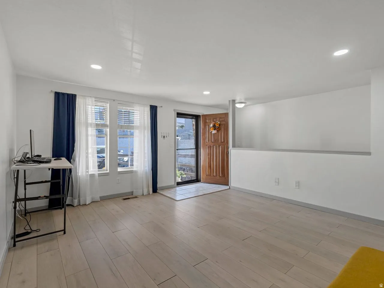 Hardwood-style flooring throughout, recessed ceiling lighting, and a paneled entry door with sidelight