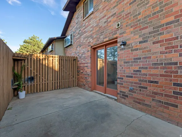 Concrete patio with a wood privacy fence, brick exterior, and sliding glass door