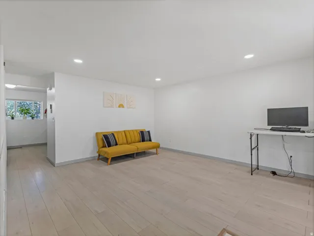 Recessed lighting, light wood-finish flooring, white wall finishes, and a window with natural light