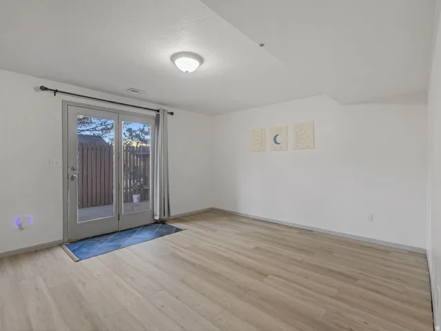 Bright, open living space with wood-finish flooring, glass sliding doors with natural light, and neutral wall finishes