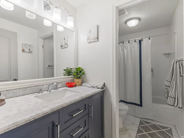 Bathroom with a navy vanity, white marble-finish countertop, and an undermount sink