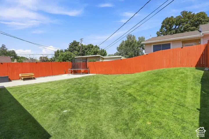 Expansive backyard featuring a large lawn, concrete patio, and a privacy fence