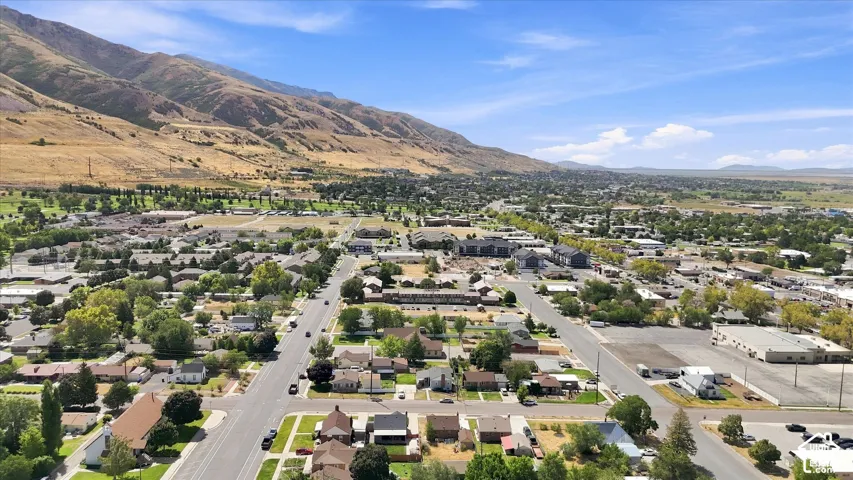 Aerial perspective capturing expansive mountainous terrain, a developed urban area, and a large flatland horizon