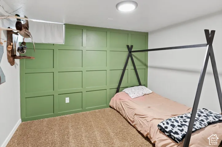 Green accent wall with paneling, flush mount ceiling light, and neutral carpet