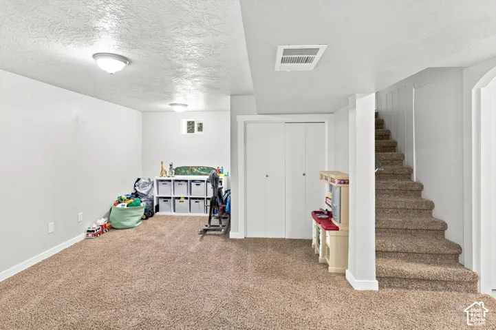 Carpeted flooring, recessed window, bi-fold closet doors, wall-mounted light fixtures, and painted walls
