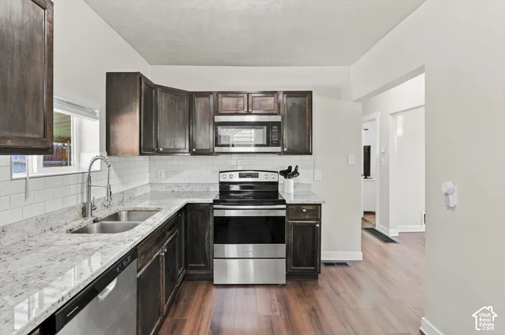 Kitchen featuring wood-finish flooring, dark wood cabinetry, white subway tile backsplash, and light-toned countertops