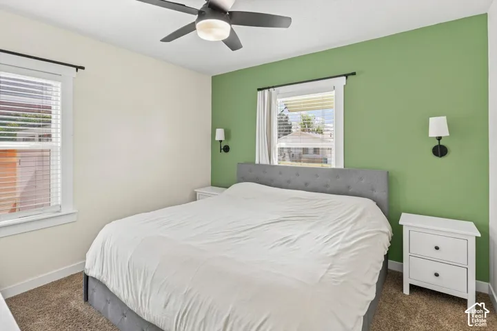 Ceiling fan with integrated lighting, multiple windows, wall-mounted sconces, and a neutral wall palette with an accent wall
