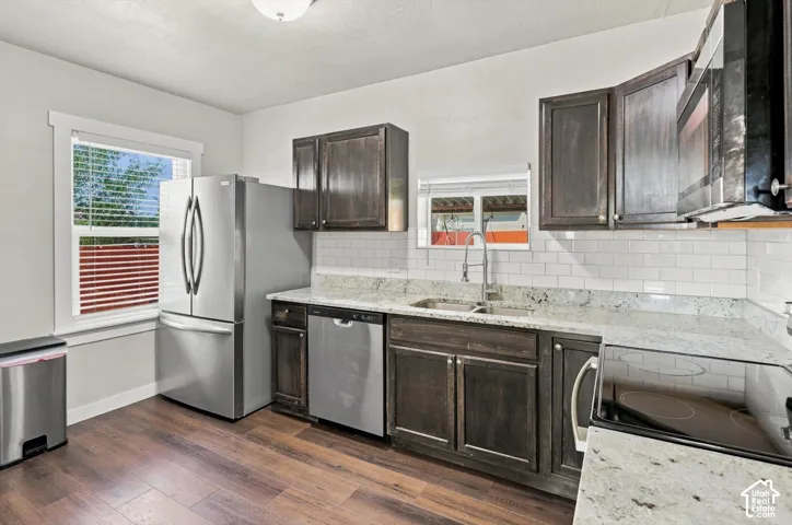 Kitchen featuring dark wood-finish cabinetry, light-toned granite countertops, and stainless steel appliances