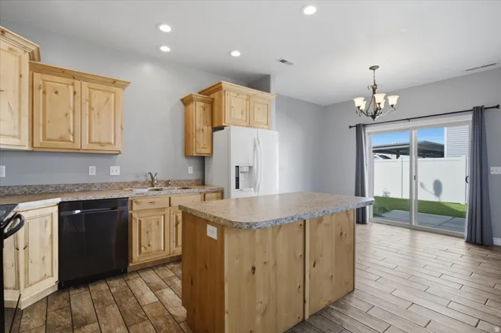 Kitchen featuring wood cabinetry, an island with a light-toned countertop, and recessed lighting