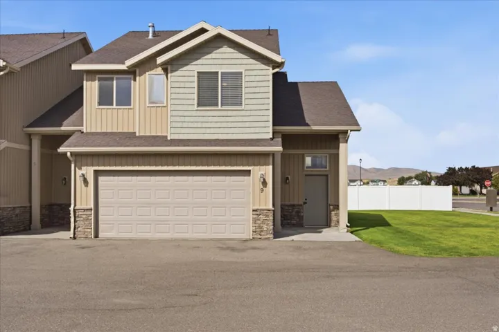 Two-story exterior with horizontal and shake siding accents, a two-car garage, and stone veneer detailing