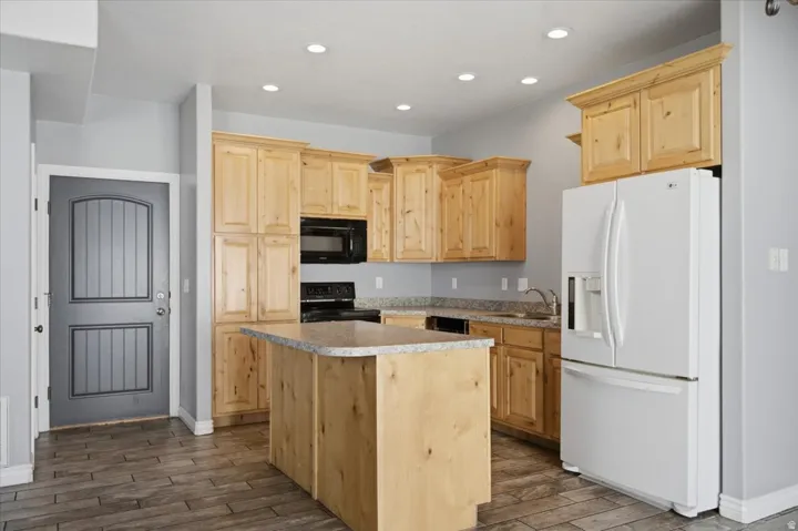 Kitchen featuring wood-finish cabinetry, granite countertops, an island with countertop seating, recessed lighting, and tile flooring