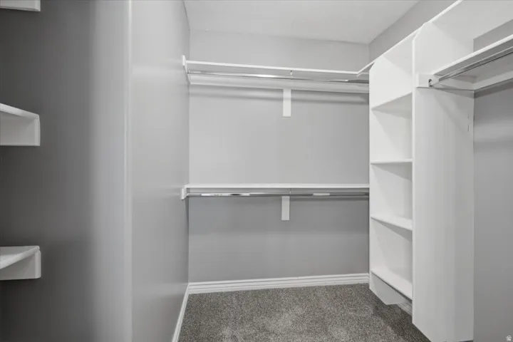 Custom closet organization system with ample shelving, multiple hanging rods, and carpeting