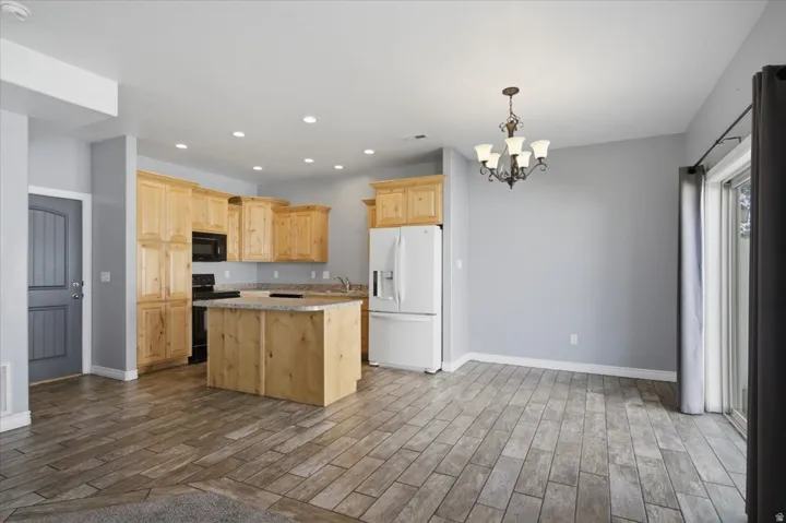 Open-concept living space with wood-finish tile flooring, recessed lighting, and a kitchen island with a stone countertop