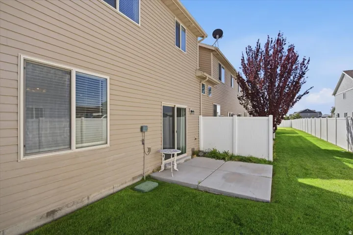 Private patio with concrete pavers, vinyl siding exterior, and a fully fenced yard with established lawn