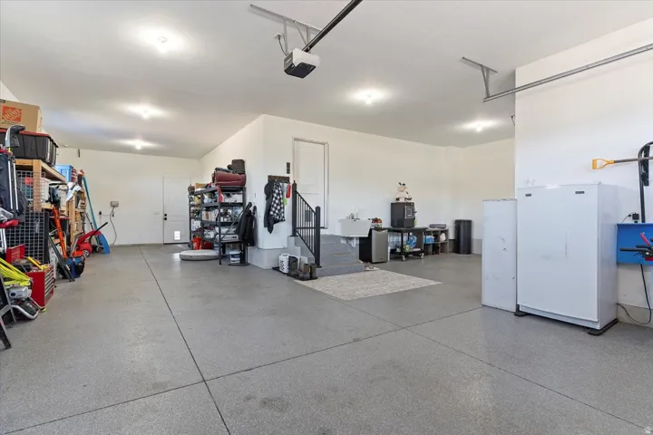 Spacious garage with epoxy flooring, recessed lighting, and direct access to interior stairs