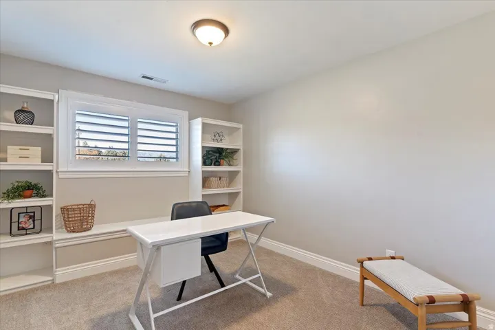Built-in shelving, window with plantation shutters, neutral carpeting, and recessed lighting