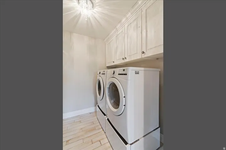 Wood-finish flooring, overhead cabinetry, and a crystal chandelier