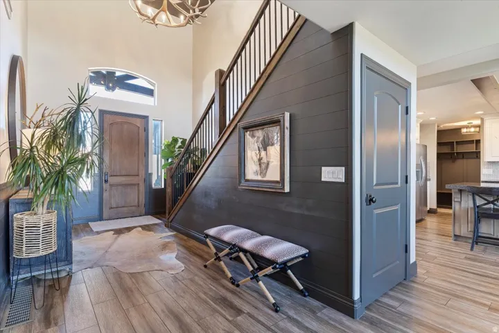 Two-story entryway with wood-finish flooring, custom wood entry door, and staircase featuring dark wood newel posts and railings