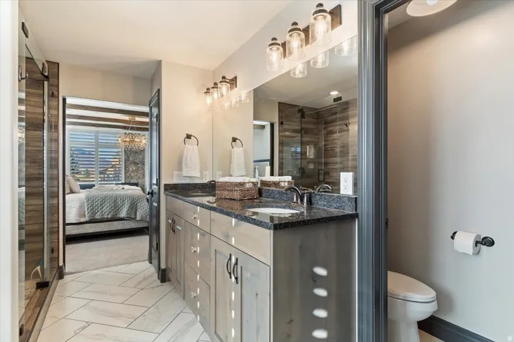 Double vanity with dark countertops and wood-finish cabinetry