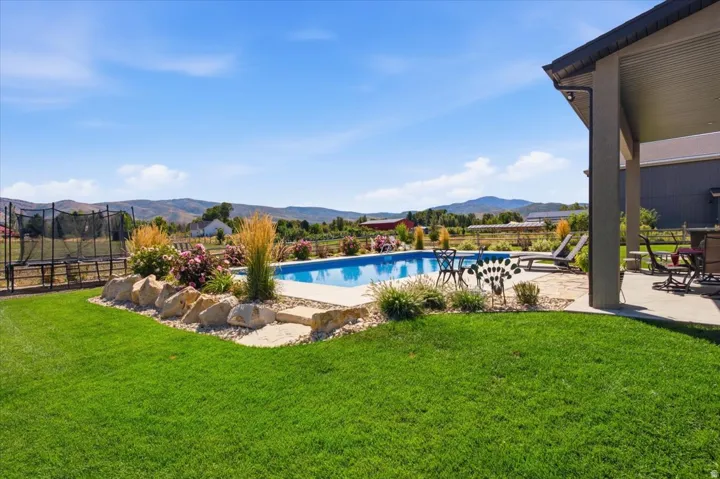 Expansive lawn with a rectangular in-ground pool, surrounded by a flagstone patio and decorative rock landscaping