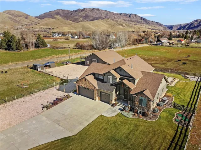 Two-story residence with a multi-level roofline, stone and siding exterior, two-car garage, and established landscaping